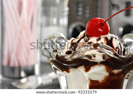 Nostalgic still life of hot fudge sundae in classic tulip dish with retro diner objects in background. Macro with shallow dof. - stock photo