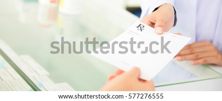 Customer (patient) giving prescription to pharmacist in pharmacy