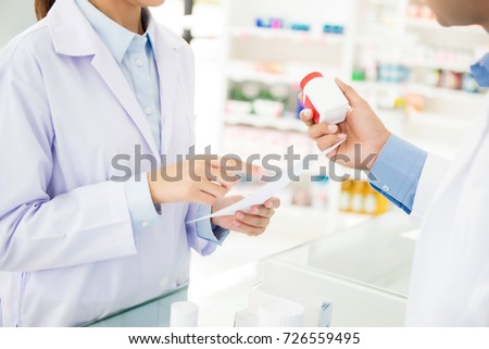 Pharmacists holding medicine bottle and discussing prescription drug in a pharmacy or drugstore