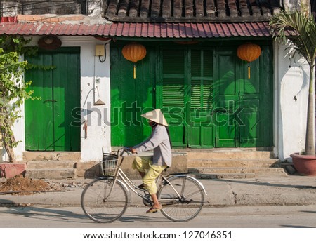HOI AN, VIETNAM - JANUARY 10: An unidentified woman rides her bicycle on January 10, 2008 in Hoi An, Vietnam. Hoi An, a UNESCO World Heritage site, is a major touristic destination in Central Vietnam.
