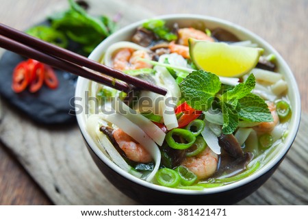 vietnamese pho tom yum - asian soup with prawns rice noodles lime shiitake mushrooms fresh mint chilli spring onions and sweet basil