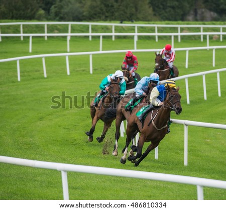 Jockeys And Race Horses Galloping Around The Bend Of Track
