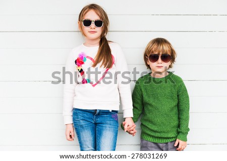 Fashion kids outdoors, wearing pullovers and sunglasses