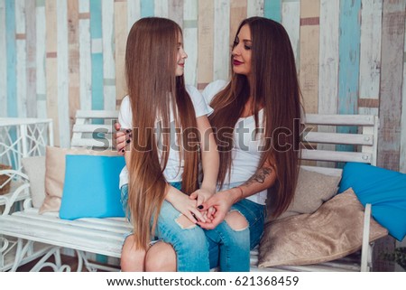 Mom and daughter with beautiful long hair and wearing the same clothes