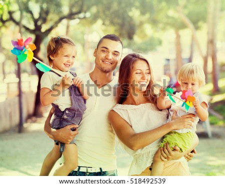 Happy parents with children playing windmills in park on sunny day