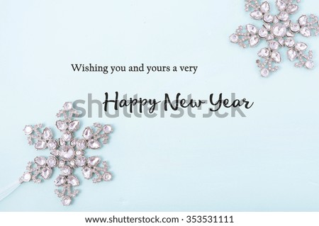Happy New Year Background with snowflake ornaments on pale blue wood with sample text greeting.