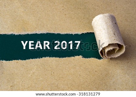 Torn brown paper on green surface with "YEAR 2017" words.