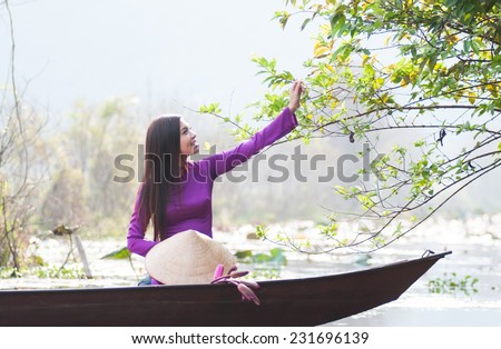 Vietnamese girl with traditional dress (ao dai) and conical hat in Yen stream in Hanoi, Vietnam