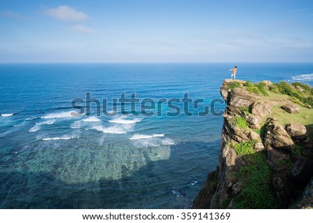 Young man in the top of the rock in Ly Son, Quang Ngai, Vietnam. Traveler explore the beach.