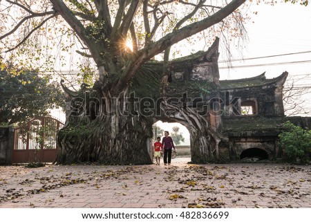 VINHPHUC, VIETNAM, APRIL 10, 2016: A boy with his grandmother go through an ancient gate in a village in Vinh Phuc province, Vietnam. Village gate is a specific of Northern country side in Vietnam.