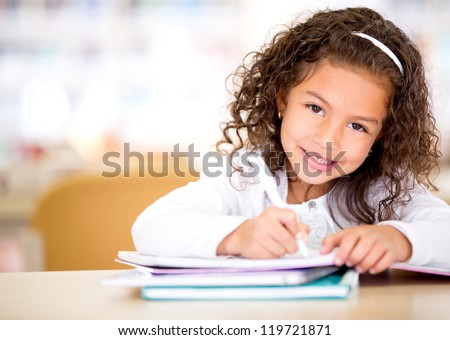 Cute little girl studying at the library and smiling