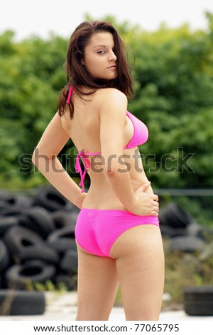 stock photo a beautiful rear view of a lovely young brunette wearing a hot pink bikini outdoors with old tires 77065795