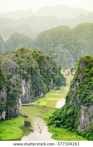 Top view of the Ngo Dong River and boats at the Tam Coc portion, Ninh Binh Province, Vietnam. Karst towers are visible in background. The Tam Coc is a popular tourist attraction in Vietnam.