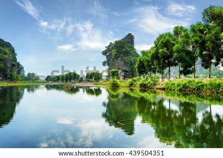 Amazing natural karst towers and green trees reflected in water of the Ngo Dong River at the Tam Coc portion, Ninh Binh Province, Vietnam. The Tam Coc is a popular tourist attraction in Asia.