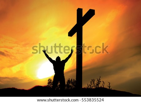 Person standing at cross with arms raised, in prayer and worship