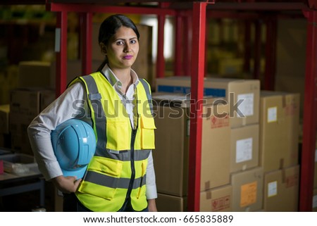 female warehouse worker with helmet and safety vest.