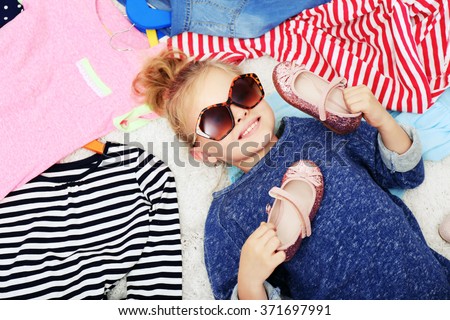 Little girl and new clothes, top view