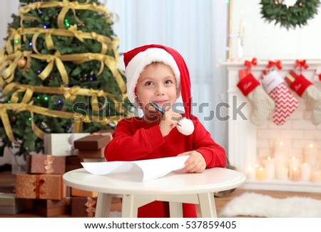 Cute little boy writing letter to Santa Claus at table