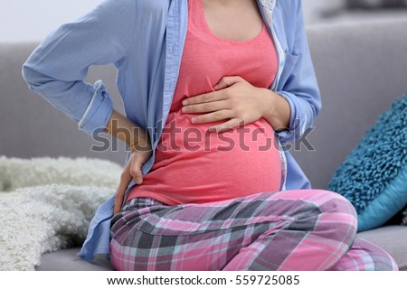 Young pregnant woman suffering from backache at home, close up