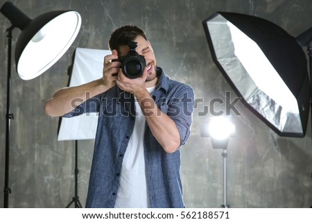 Young male photographer in studio with professional lighting equipment