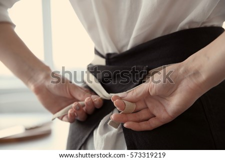 Woman tying up her apron around the waist
