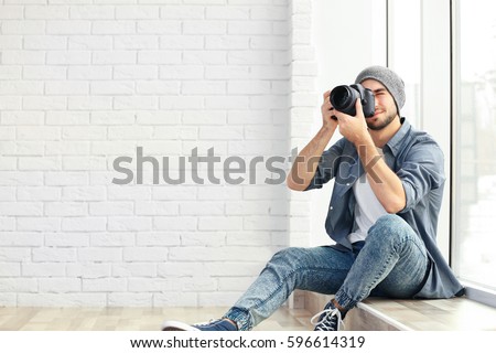 Handsome young photographer sitting on window sill