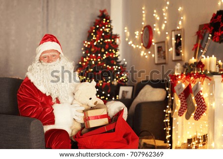 Santa Claus with gift bag in room decorated for Christmas