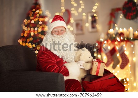 Santa Claus with gift bag in room decorated for Christmas