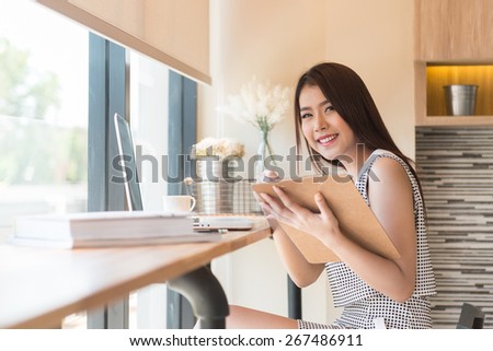 Beautiful business woman using a laptop computer and writing on business document