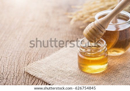 Honey with wooden honey dipper on wooden table