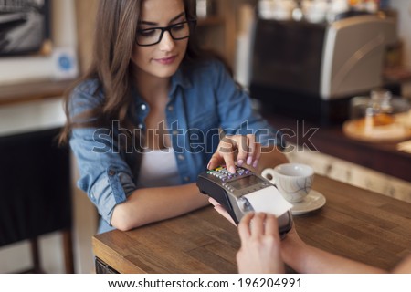 Young woman paying for cafe by credit card reader
