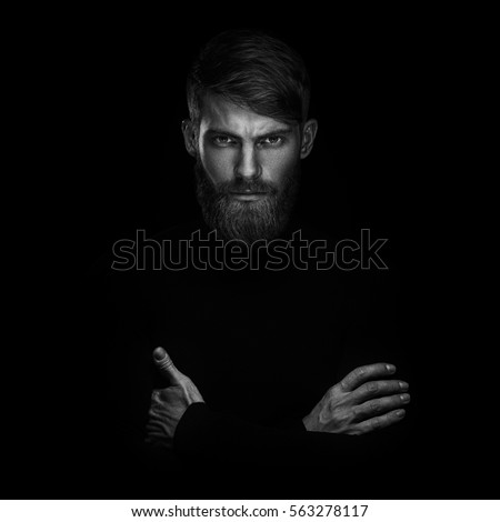 Black and white portrait of serious young man with folded and crossing hands standing isolated on Black and white portrait of serious young man with folded and crossing hands standing isolated on