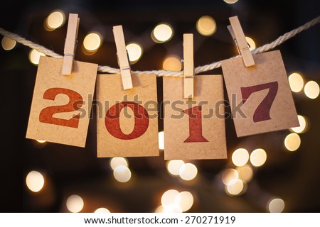 The word 2017 spelled out on clothespin clipped cards in front of glowing lights.