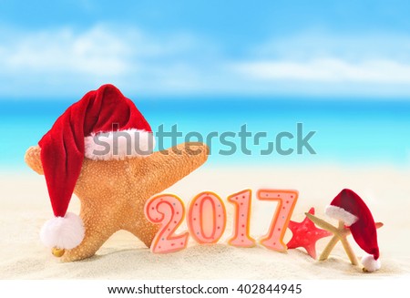 Happy New Year 2017. Starfish in Santa hat on the summer beach.