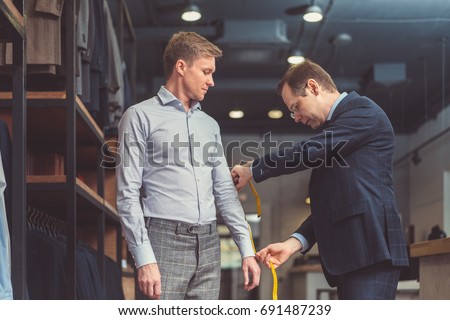 Mature tailor and customer in atelier