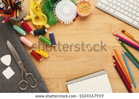Fashion designer workspace top view. Sewing equipment, colored pencils, laptop and notepad on wooden table with copy space