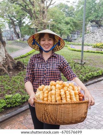 HANOI, VIETNAM, 19TH MARCH 2017: A local lady in Hanoi selling sweet treats. The lady is wearing a traditional cone hat common on Vietnam