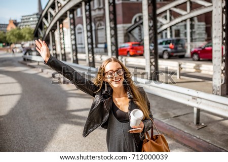 stock-photo-young-stylish-businesswoman-with-coffee-cup-catching-a-taxi-on-the-old-iron-bridge-712000039.jpg