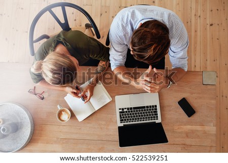 Top view of man and woman sitting at table and working. Two people working together on laptop.