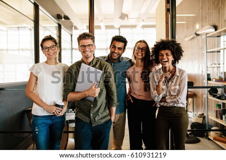 Portrait of creative business team standing together and laughing. Multiracial business people together at startup.