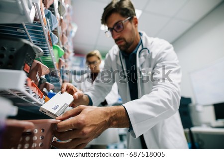 Pharmacist looking for a drug on shelf. Male pharmacist checking stock in an shelf. Medical staff working in hospital pharmacy.
