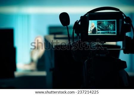 Young beautiful blonde television announcer at studio during live broadcasting.Female TV director at editor in studio.Recording at TV studio with television anchorwoman. TV NEWS studio with camera