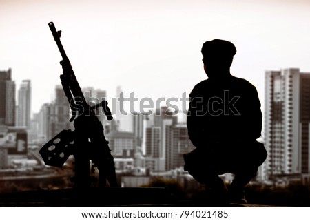 Silhouette of infantry soldier with machine gun sitting to guard on blur citscape background