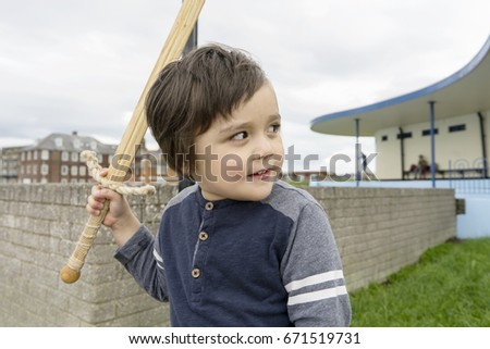 stock-photo-happy-toddler-boy-playing-outdoor-with-wooden-sword-kid-holding-sword-toy-671519731.jpg