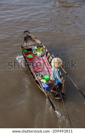 Man in asian conical hat is floating down Mekong river on wooden boat, Can Tho Floating Market, Mekong Delta, Vietnam.