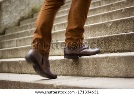 Walking upstairs: close-up view of man's leather shoes (motion blurred image)