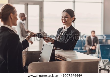 happy businesswoman giving passport and ticket to staff at airport check in counter
