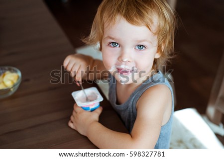 Cute little boy eating yogurt.