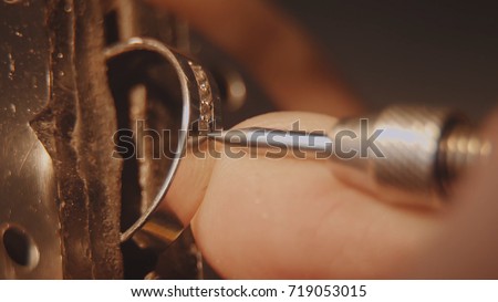 The jeweller is setting a precious stone. Craft jewelery making. Ring repairing. Putting the diamond on the ring. Macro video. Craft jewelery making with professional tools. Putting the diamond on the