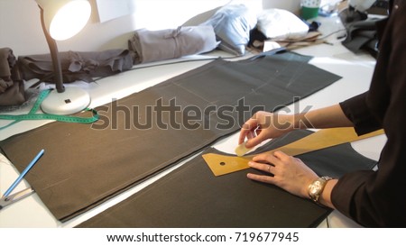 Tailor.Hands notch tailor tailor's scissors cloth. Female tailor stitching material at workplace. Preparing fabric for clothes making. Tailoring, garment industry, designer workshop concept.